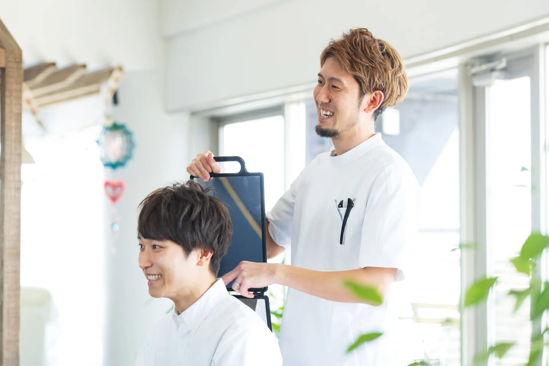 手鏡で仕上がりを確認するお客様とスタイリスト