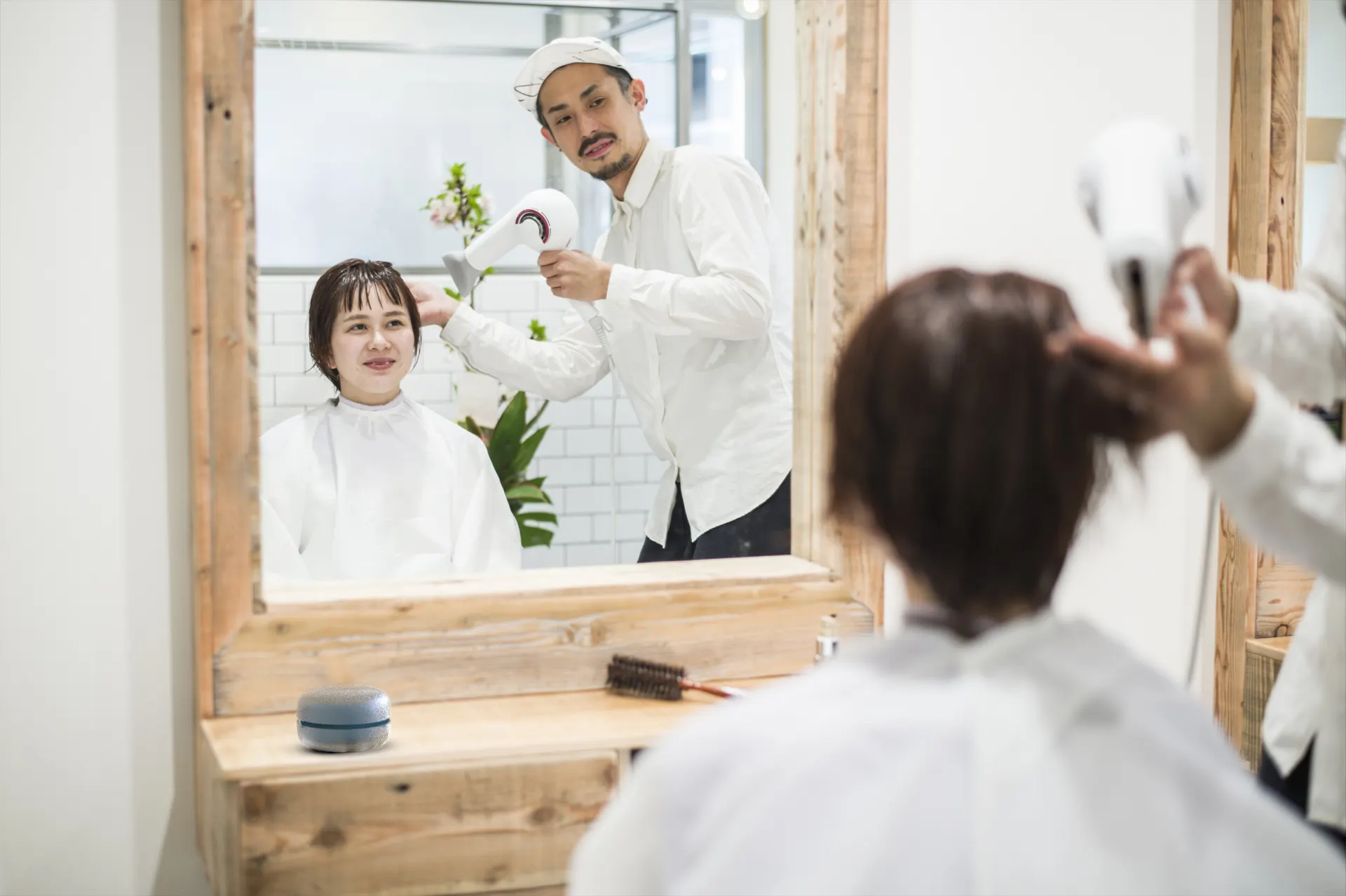 美容サロンでお客様の髪を乾かすスタイリスト